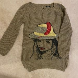 I am selling A size Xs gold-coloured sweater with a girl's print on the front.